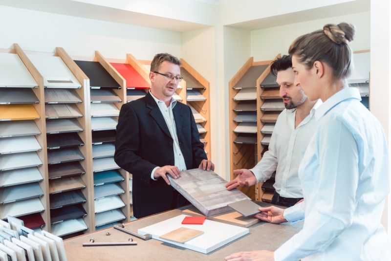 Schreiner zeigt Kunden verschiedene Materialmuster in der Ausstellung